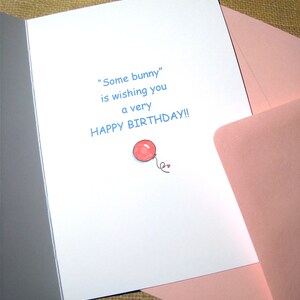 May include: A white card with blue text that reads "Some bunny" is wishing you a very happy birthday! A red balloon with a string is drawn in the bottom right corner.