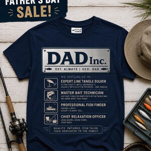 May include: A navy blue short-sleeve t-shirt featuring a graphic of a silver metal sign that reads DAD Inc. EST. ALWAYS | CEO: DAD. Below the text are four icons with descriptions: Expert Line Tangle Solver, Master Bait Technician, Professional Fish Finder, and Chief Relaxation Officer.