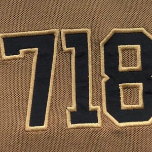Close-up of large embroidered “718” number on fabric