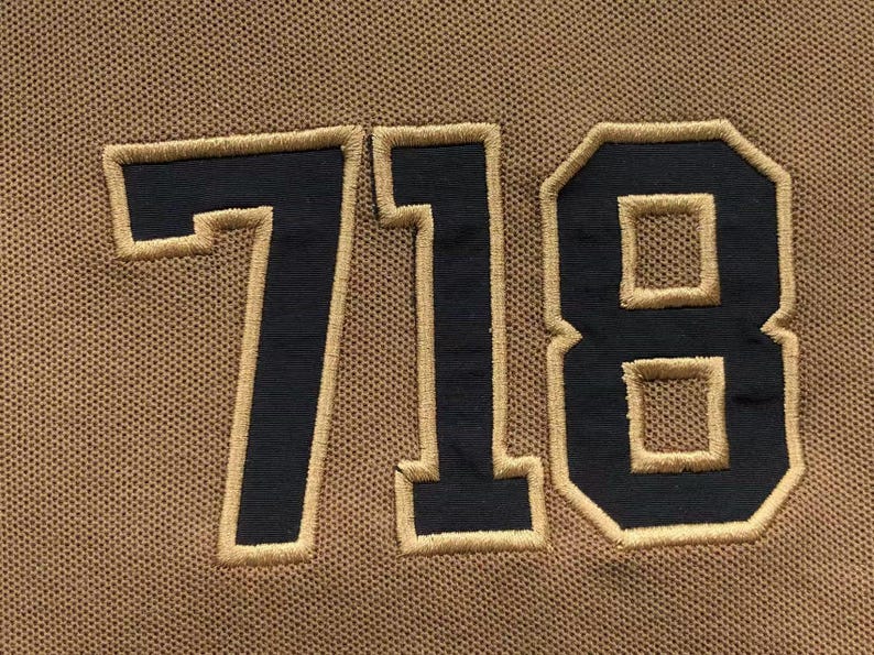 Close-up of large embroidered “718” number on fabric