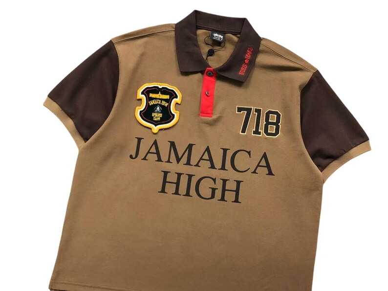 Front angled view of brown polo shirt with “Jamaica High” embroidery