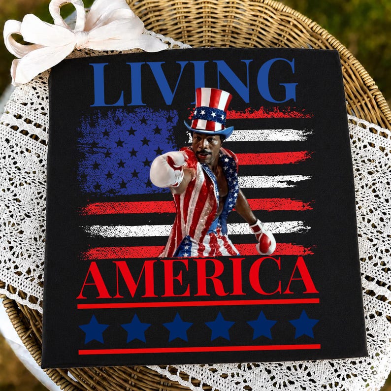 May include: A black square sign featuring the text LIVING AMERICA in blue and red. The centre shows a boxer wearing a red, white, and blue top hat and matching boxing trunks with white gloves, set against a distressed American flag background.