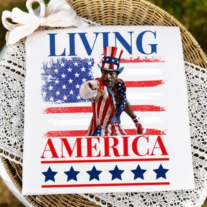 May include: A white square sign featuring the text LIVING AMERICA in blue and red. The centre displays a man wearing a red, white, and blue top hat and boxing attire, positioned over a distressed American flag graphic. Six blue stars line the bottom.