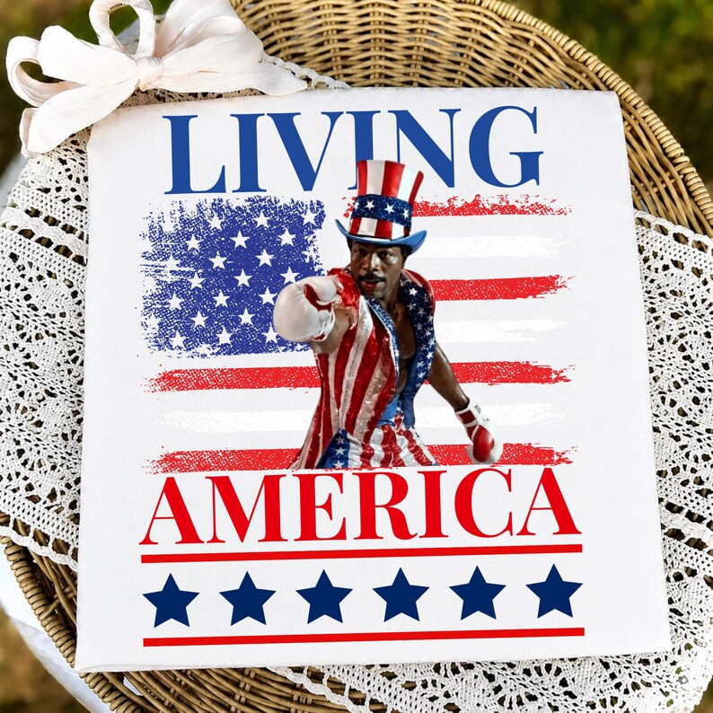 May include: A white square sign featuring the text LIVING AMERICA in blue and red. The centre displays a man wearing a red, white, and blue top hat and boxing attire, positioned over a distressed American flag graphic. Six blue stars line the bottom.