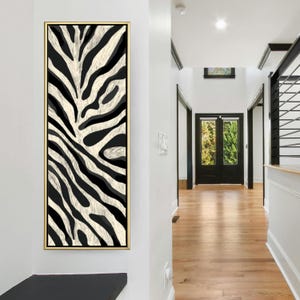 Könnte beinhalten: Ein gerahmtes Leinwandkunstwerk mit einem schwarz-weißen Zebrastreifenmuster. Das Kunstwerk ist rechteckig und vertikal ausgerichtet, mit einem goldfarbenen Rahmen. Der Zebrastreifen hat ein natürliches, strukturiertes Aussehen.