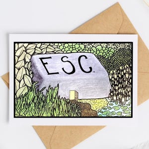 May include: A greeting card with a hand-drawn illustration featuring a large rock with the letters "ESC" on it. The rock is surrounded by greenery, a small building, and a pond. The card is on a white surface with a brown envelope.