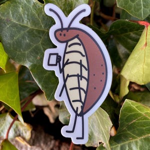 May include: A sticker featuring a cartoon cockroach holding a small cup. The cockroach is brown with a cream-colored underbelly and black details. The sticker has a white border and is set against a background of green leaves.