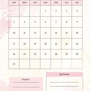 Op de afbeelding: Een roze en witte mei 2026 kalender met een aquarelontwerp. De kalender bevat een takenlijst en een sectie voor topprioriteiten. Het woord "May" is in een scriptlettertype geschreven.