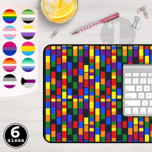 Peut inclure: Un tapis de bureau coloré avec un motif géométrique de rectangles verticaux de différentes couleurs. Le tapis est à côté d'un clavier, d'un stylo avec le texte "DAY DREAMING" et d'un ensemble de drapeaux de la fierté. Le texte "6 sizes" est également visible.