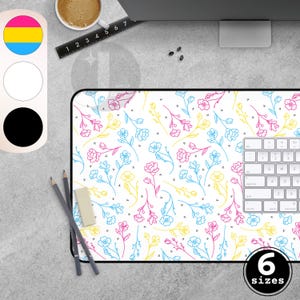Peut inclure: Un tapis de bureau blanc avec un motif floral rose, bleu et jaune. Le tapis a une bordure noire et un clavier sur le côté droit. Le texte "6 sizes" est dans un cercle noir en bas à droite.