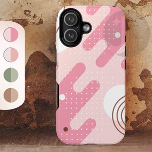 May include: A pink and white phone case with a geometric design. The case features a pattern of pink shapes, white circles, and small white dots. The phone case has a black camera cutout and a white border.