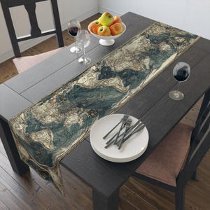 May include: A dark gray wooden dining table set with a decorative table runner featuring a vintage world map design in shades of blue, beige, and brown. The table is set with white plates, forks, wine glasses, and a bowl of apples.