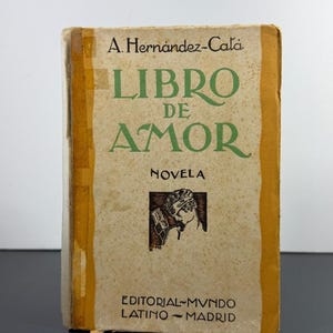 May include: A vintage book titled Libro de Amor by A. Hernández-Catá, featuring a beige cover with green text, a small black and white illustration of a person, and the publisher information Editorial Mundo Latino Madrid printed at the bottom.