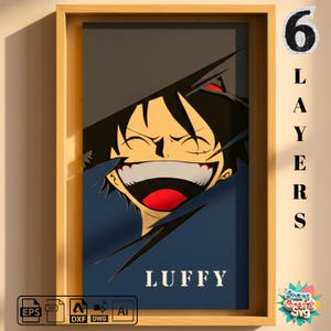 Op de afbeelding: Een ingelijst kunstwerk met een lachend stripfiguur met zwart haar en een rode mond. Het gezicht van het personage is gelaagd tegen een blauwe achtergrond met de naam "LUFFY" in het wit. De lijst is gemaakt van lichtbruin hout. De tekst "6 LAYERS" is ook inbegrepen.