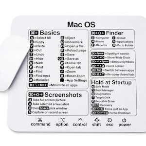 May include: A white rectangular mouse pad featuring black printed text and icons for Mac OS keyboard shortcuts, including sections for Basics, Finder, Screenshots, and Startup commands, accompanied by a white wireless computer mouse.