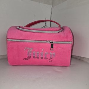Front view of the pink velvet travel case showcasing its rhinestone Juicy logo and silver zippers.