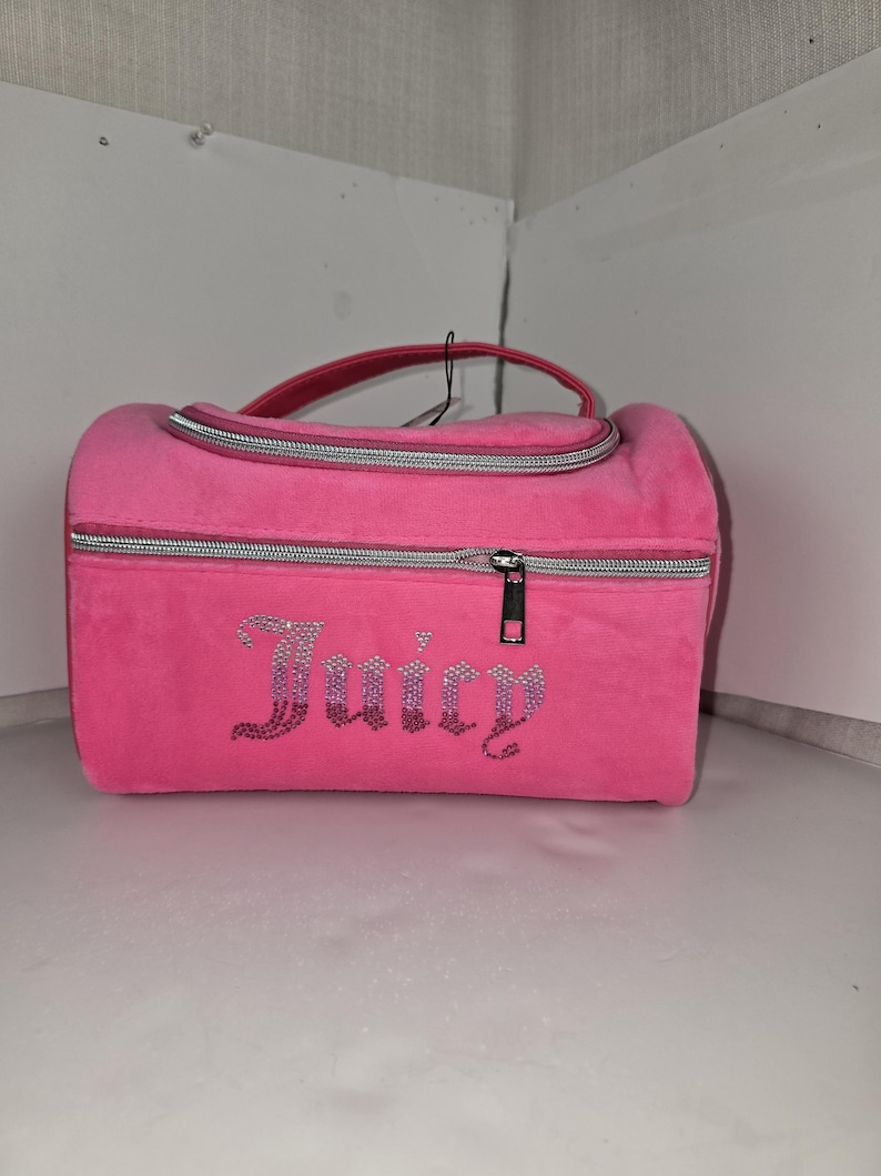 Front view of the pink velvet travel case showcasing its rhinestone Juicy logo and silver zippers.