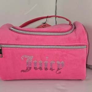 Front view of a pink velvet cosmetic bag featuring the word Juicy spelled in rhinestones.