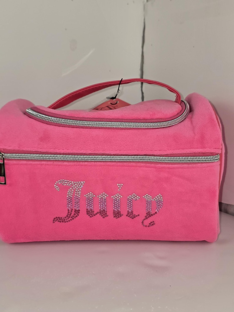 Front view of a pink velvet cosmetic bag featuring the word Juicy spelled in rhinestones.