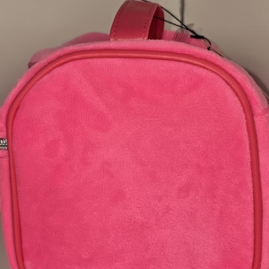 Side profile view showing the rounded end of the pink velvet bag.
