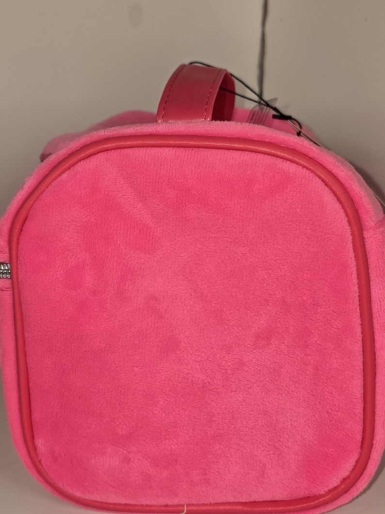 Side profile view showing the rounded end of the pink velvet bag.