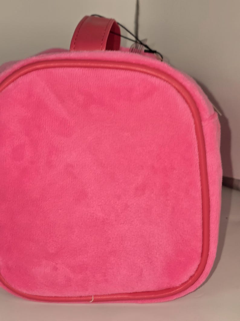 Close-up of the circular side panel of the pink velvet cosmetic case.