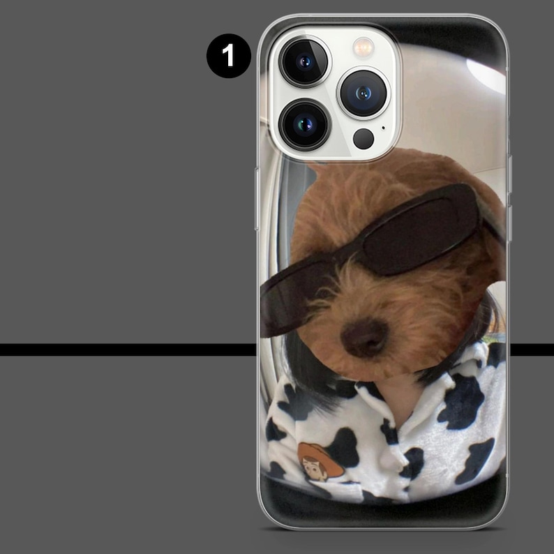 May include: Clear phone case featuring a brown dog wearing sunglasses and a black and white patterned shirt. The dog's face is centered, with the camera lenses visible at the top. The case has a clear border.