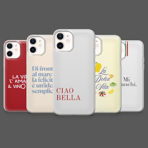 Op de afbeelding: Vijf telefoonhoesjes met verschillende ontwerpen en tekst. De hoesjes bevatten zinnen als "Ciao Bella" en "La Dolce Vita" in rode en zwarte lettertypen. De hoesjes zijn rood, wit en geel.