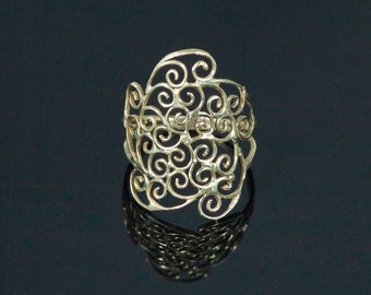 May include: A gold ring with a delicate, intricate design of swirling patterns. The ring is made of metal and has a smooth, polished finish.