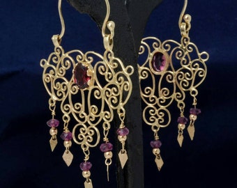 May include: A pair of gold filigree earrings with dangling purple gemstones. The earrings have a delicate, intricate design and are perfect for adding a touch of elegance to any outfit.