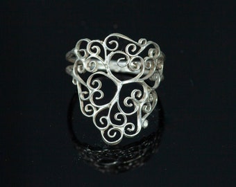 May include: A silver filigree ring with a delicate, intricate design. The ring is made of thin, twisted wires that form a pattern of swirls and loops.