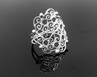 May include: A silver filigree ring with a delicate, intricate design. The ring is oval-shaped and features a repeating pattern of swirls and loops.