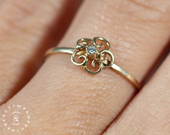 May include: A delicate gold ring with a small diamond set in a floral design.