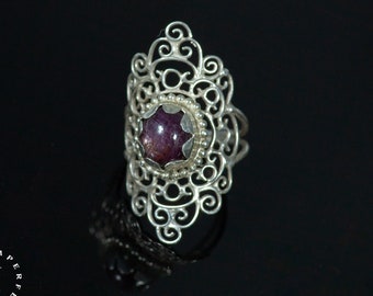 May include: A silver ring with a delicate filigree design and a purple gemstone in the center.