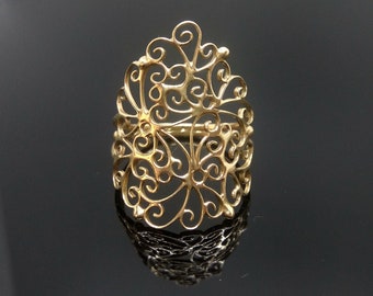 May include: A gold filigree ring with a delicate, intricate design. The ring is made of a thin, delicate metal and has a floral pattern.