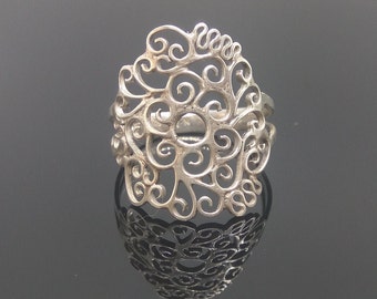May include: A silver filigree ring with a delicate, intricate design resembling a flower or a tree branch. The ring is made of thin, twisted wires that create a lacy effect.