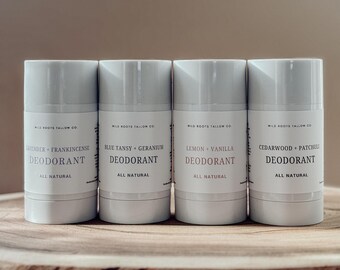 May include: Four white deodorant sticks with labels. The labels read "Lavender + Frankincense", "Blue Tansy + Geranium", "Lemon + Vanilla", and "Cedarwood + Patchuli". The text "Deodorant" and "All Natural" are also on the labels. The sticks are on a wooden surface.