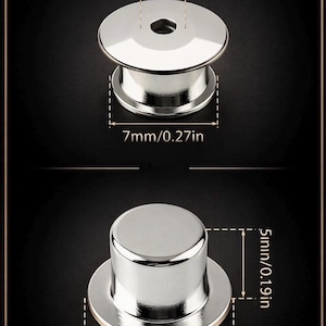 May include: Two silver-colored metal pin backs. The top pin back is 7mm (0.27in) wide and 1mm (0.04in) thick. The bottom pin back is 10mm (0.39in) wide and 5mm (0.19in) tall. Both have a shiny, reflective surface.