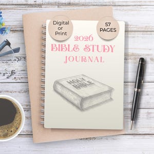 Op de afbeelding: Een spiraalgebonden 2026 Bijbelstudie Journal met 57 pagina's, met de tekst "2026 Bible Study Journal" in roze. De omslag bevat een schets van een Bijbel. Een zwarte pen, een kopje koffie en een bril zijn ook zichtbaar.