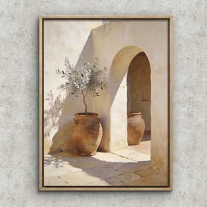 Könnte beinhalten: Gerahmter Kunstdruck, der eine sonnige mediterrane Szene zeigt. Ein Terrakotta-Topf enthält einen Olivenbaum, der einen Schatten auf eine cremefarbene Wand wirft. Ein gewölbter Durchgang zeigt einen weiteren Topf und einen Blick auf einen sonnigen Innenhof. Das Kunstwerk ist in hellem Holz gerahmt.