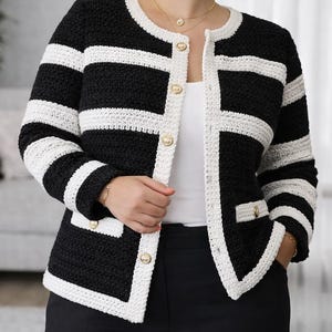 May include: A black and white crochet jacket with gold buttons and white trim. The jacket features horizontal stripes and a classic design. The jacket has two front pockets. The jacket is suitable for various occasions.