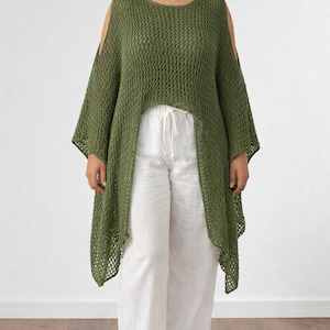 May include: Olive green crochet top with open shoulders and long sleeves. The top has a high-low hemline and is paired with white wide-leg pants. The outfit is displayed against a plain white background.