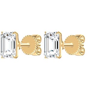 May include: A pair of stud earrings featuring emerald-cut clear stones set in yellow gold prongs. Each earring includes a matching yellow gold post and a textured, circular screw-back closure, showcasing a clean, metallic finish throughout.