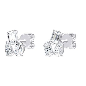 May include: A pair of silver-toned stud earrings, each featuring a cluster of three clear, faceted stones. The arrangement includes one rectangular emerald-cut stone positioned above two oval-cut stones, all secured with metal prongs and posts.