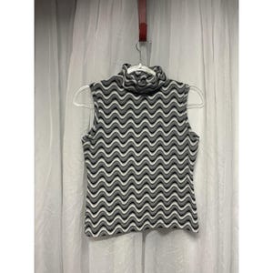 May include: Sleeveless turtleneck top with a wavy pattern in shades of gray, black, and white. The top is hanging on a clear hanger against a white curtain backdrop. The fabric appears to be a knit or similar material.