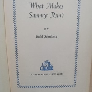 May include: The cover of the book "What Makes Sammy Run?" by Budd Schulberg. The title is in a decorative font, with a blue border and a small illustration of a building. Published by Random House, New York.