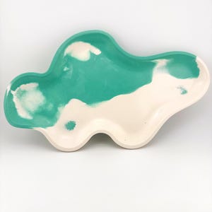 May include: A cloud-shaped decorative tray with a two-tone design. The tray features a teal and off-white color scheme. The teal section has a marbled effect, while the off-white section is solid. The tray is made of a smooth material and has a glossy finish.