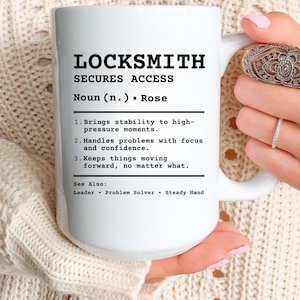 Puede incluir: Taza de cerámica blanca con la palabra "LOCKSMITH" en negro. La taza incluye una definición, enumerando cualidades como "SECURES ACCESS" y "Maneja los problemas con enfoque y confianza."