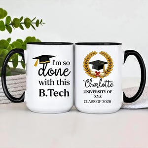 May include: Two white ceramic mugs with black handles and rims. One mug reads "I'm so done with this B.Tech" with a graduation cap graphic. The other mug features a graduation cap, laurel wreath, the name "Charlotte", and "University of XYZ, Class of 2026."