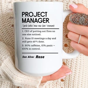 May include: White ceramic mug with the text "PROJECT MANAGER" in black, along with a definition. The definition includes phrases like "CEO of putting out fires" and "90% caffeine, 10% panic." The mug also says "See Also: Rose."